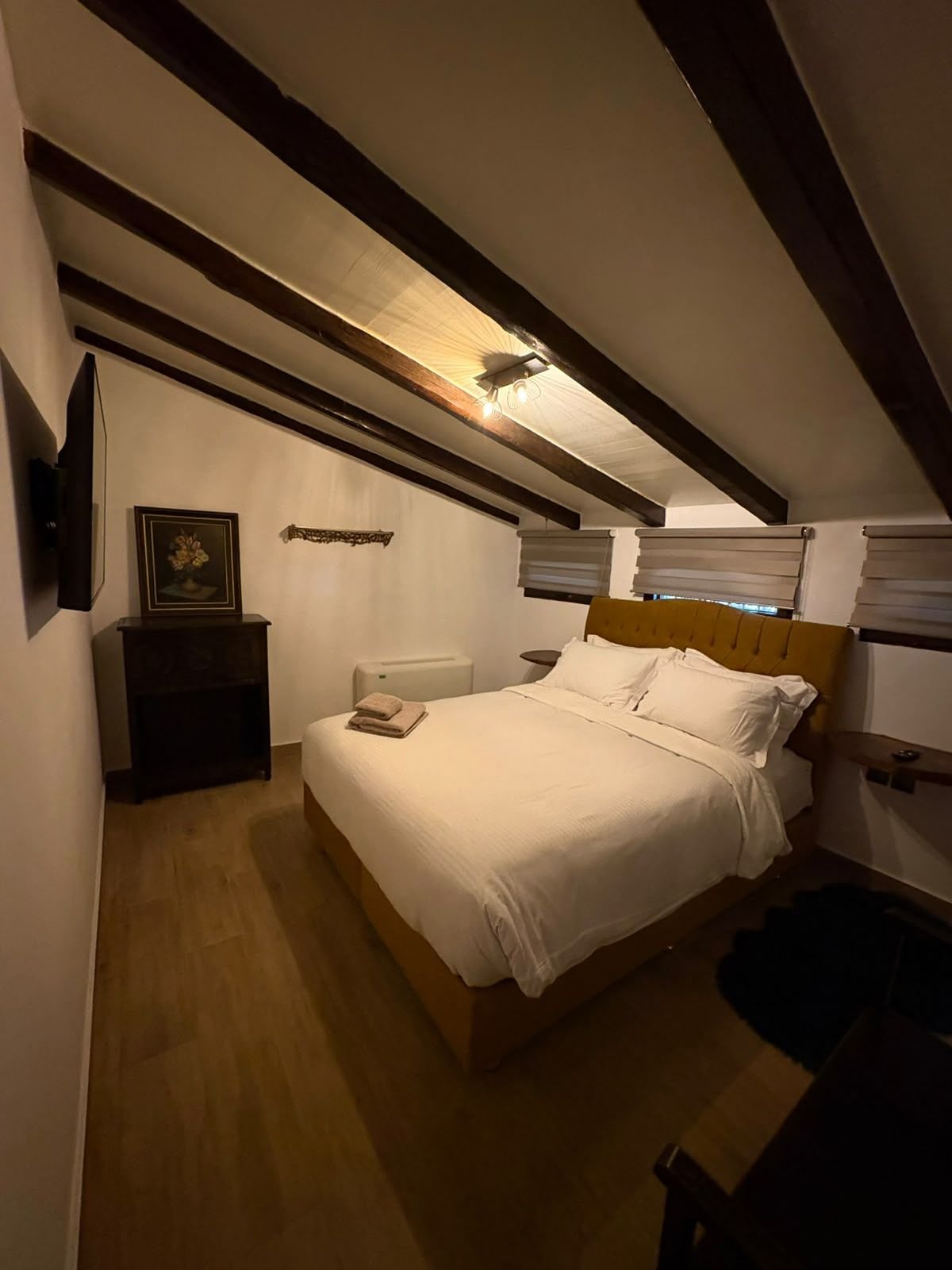 Un dormitorio con cama de madera, una mesita de noche, un cuadro enmarcado y un ventilador de techo.