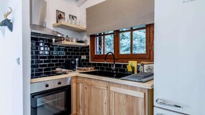 A kitchen with black tiled backsplash, wooden cabinets, a stainless steel oven, and a white refrigerator. - MZ Reindeer (Distomo-Arachova-Antikyra)