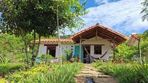 A house with a tiled roof, a hammock, and a stone pathway leading to the entrance.