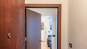 A wooden door leading to a hallway with a bed and a wall-mounted shelf. - [Savona Old Town] Cruises 10 mins • Free WIFI (Savona)