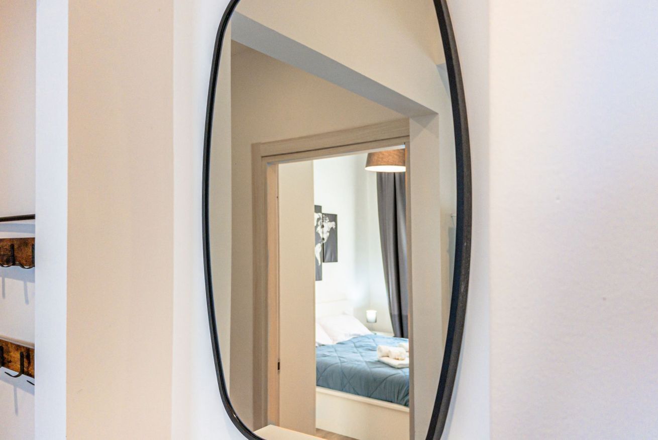 Ein Spiegel zeigt ein Schlafzimmer mit einem Bett, einem Nachttisch und einer Lampe.