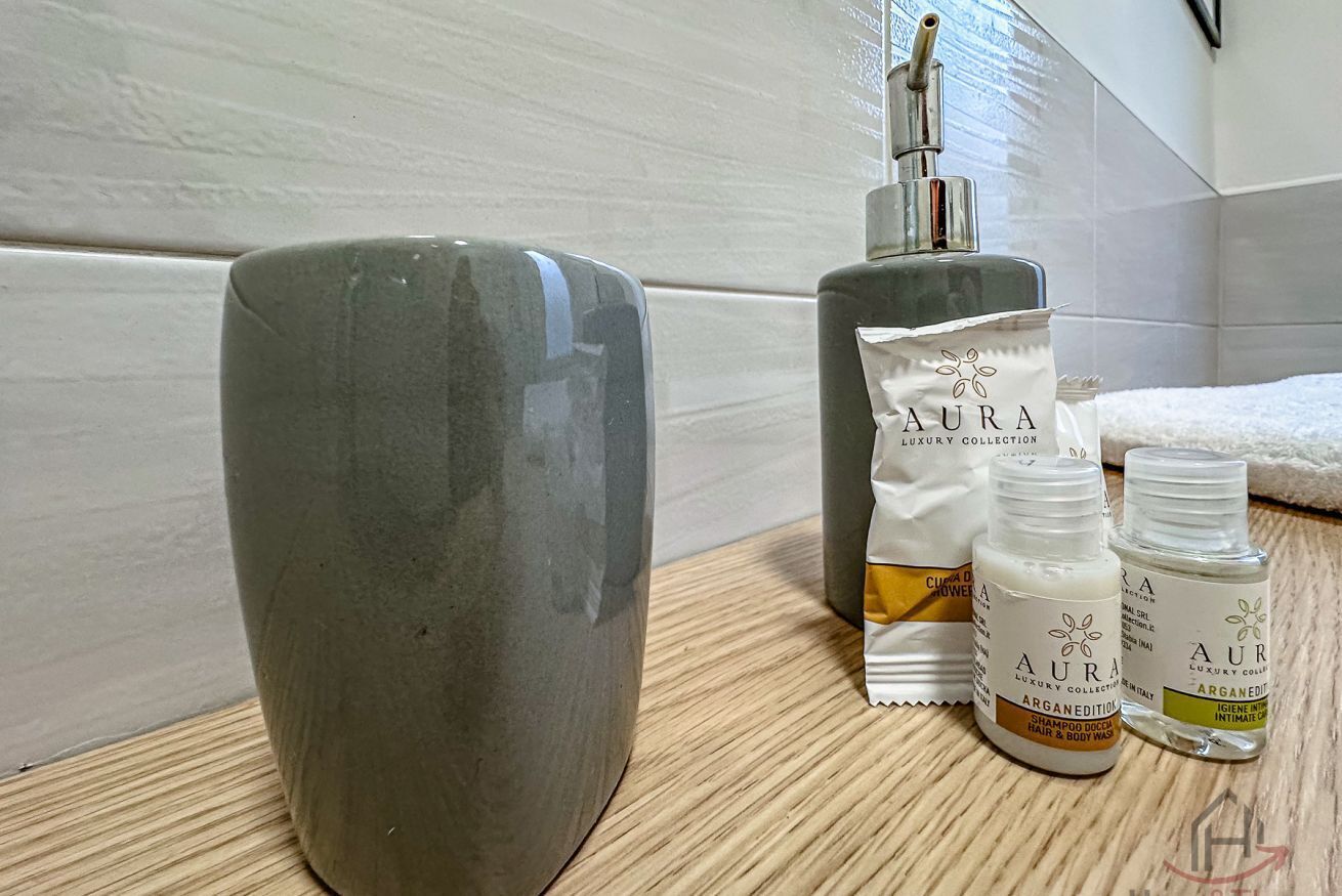 Une salle de bain avec un lavabo en céramique gris, un flacon de shampoing et un flacon de lotion.