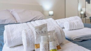 A hotel room with neatly folded white towels, a bed with a blue bedspread, and a nightstand with a lamp. - [Savona Old Town] Cruises 10 mins • Free WIFI (Savona)