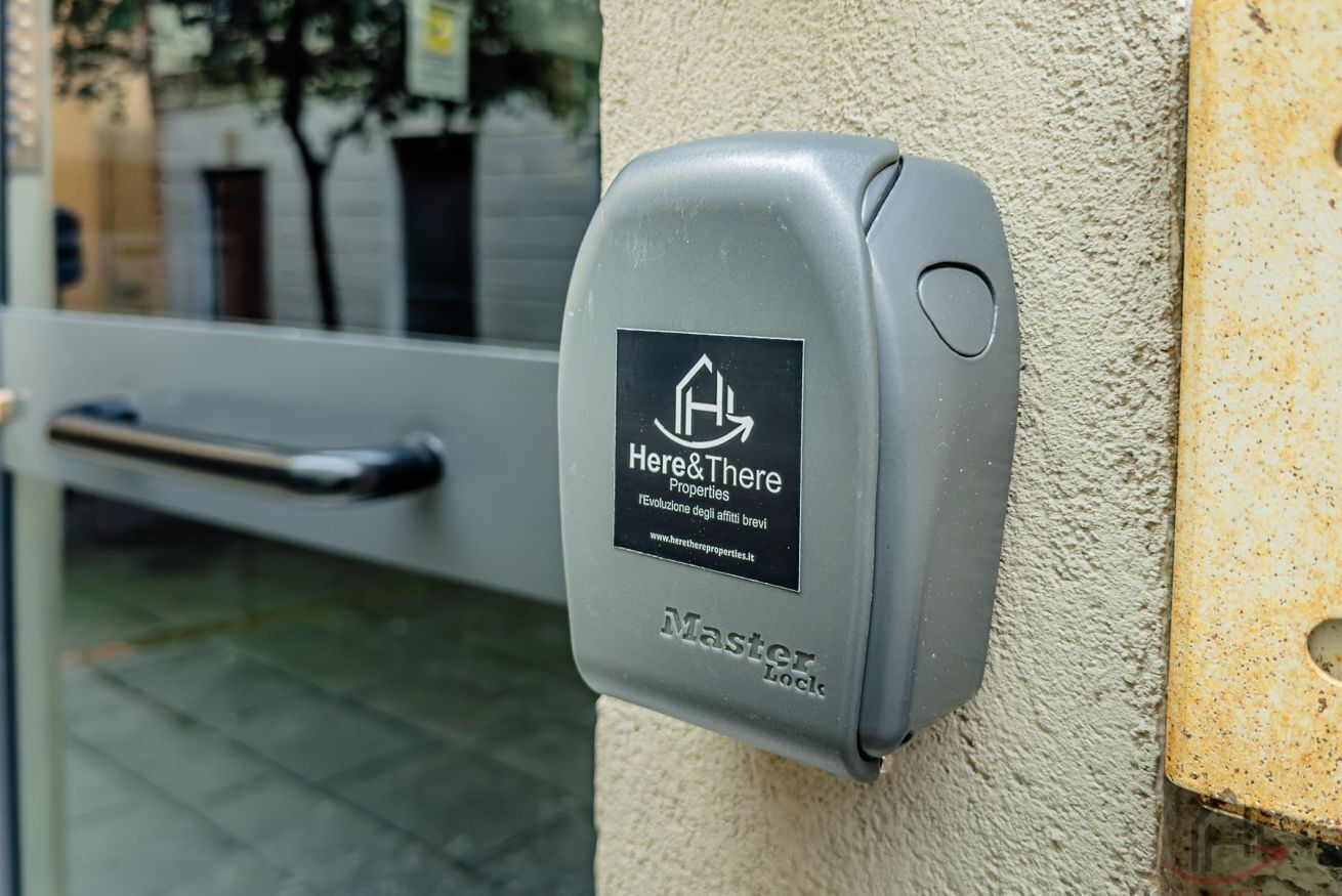 Un appareil électronique gris, fixé à un mur texturé, et portant un logo et du texte indiquant qu’il s’agit d’un système de gestion immobilière pour un hôtel.