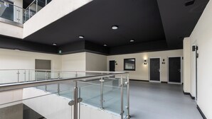 Eine moderne Hotelhalle mit Glastrennwand, einer Treppe und einer flachen Decke.