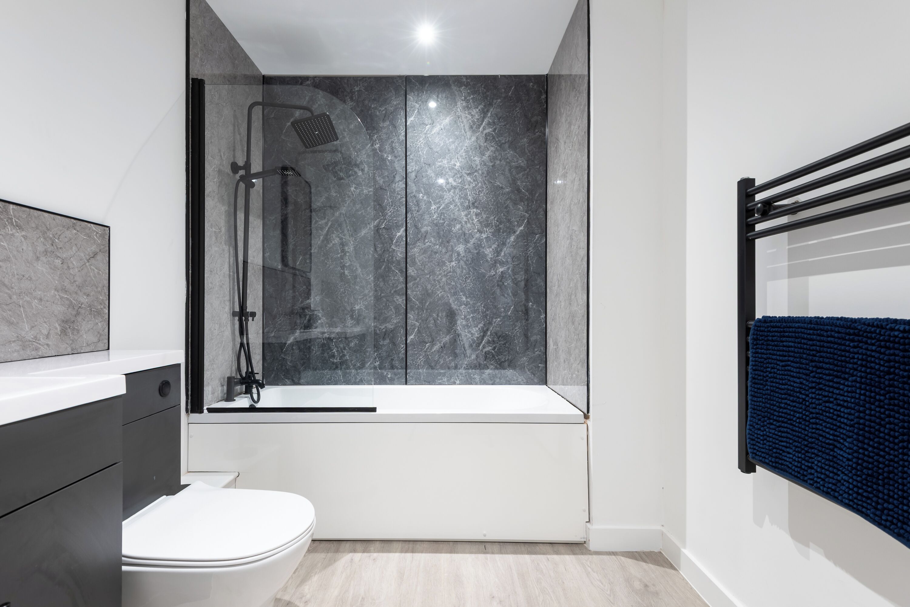 Un baño moderno con ducha envuelta en vidrio, inodoro blanco y bañera.