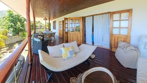 A wooden deck with a sofa, a dining area, and a view of the outdoors.