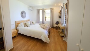 A bedroom with a wooden bed, a bedside table, a chair, a desk, and a wardrobe.