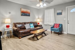 A living room with a brown leather sofa, a wooden coffee table, a blue armchair, and two lamps on side tables. - Nature's Nook I Cozy 2BR I 15m to RRG I Wi-Fi (Stanton)