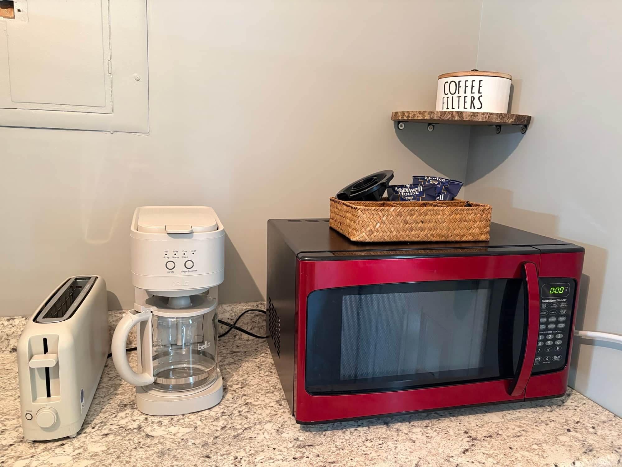 A kitchenette with a red microwave, a coffee maker, and a toaster.
