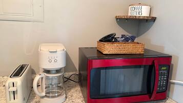 A kitchenette with a red microwave, a coffee maker, and a toaster.