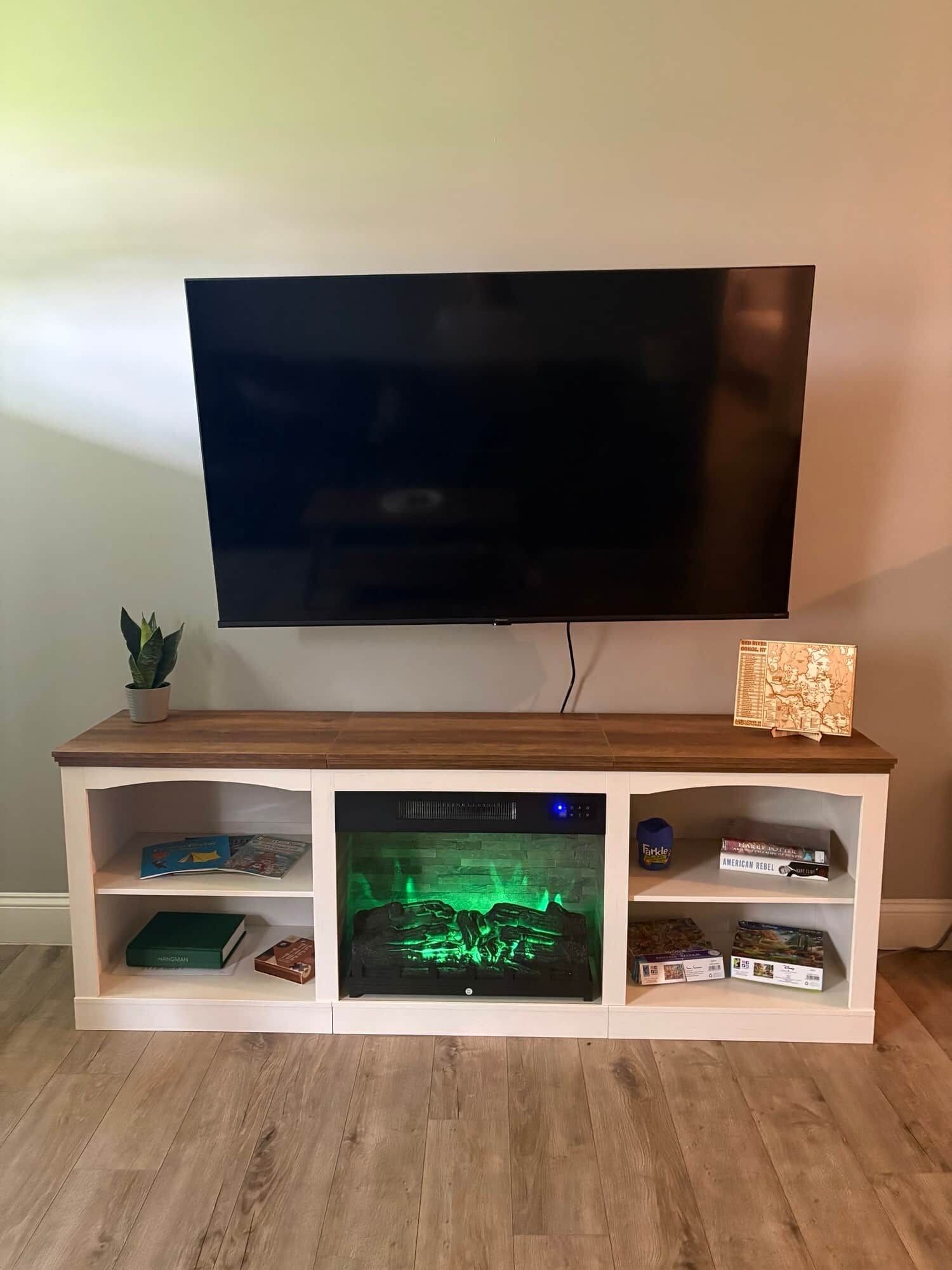 A flat-screen TV mounted on a wooden entertainment center with shelves below.
