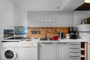 A compact kitchen with a washing machine, a coffee maker, and a microwave. - Holiday Home "Sous les pins" with Private Garden, Wi-Fi and Air Conditioning (La Garde)