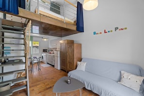 A loft-style room with a bunk bed, a kitchenette, a dining area, and a sofa. - Holiday Home "Sous les pins" with Private Garden, Wi-Fi and Air Conditioning (La Garde)