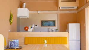 Une cuisine compacte comprenant un coin repas, un four encastré, un réfrigérateur et un climatiseur fixé au mur.
