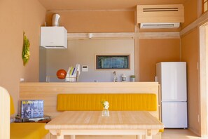 A compact kitchen with a dining area, a built-in oven, a refrigerator, and a wall-mounted air conditioner. - Setouchi, Onomichi Mukojima｜Ionchi-house Kasumi with garden｜Base of operations on the Shimanami Kaido｜2 parking spaces (尾道市向島町)