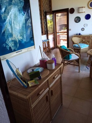 Habitación con un mapa grande, muebles de mimbre y vistas a través de una puerta.