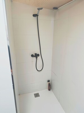 Een douche, handdoeken, zeep, toiletpapier