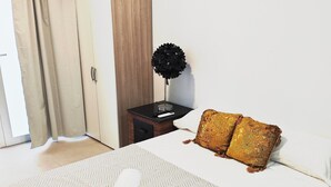 A neatly made bed with a white and grey herringbone bedspread, a red and white towel, and two golden pillows. - Studio MARQ CASTILLO Alicante Playa. Clean and complete. Well communicated. (Alacant)
