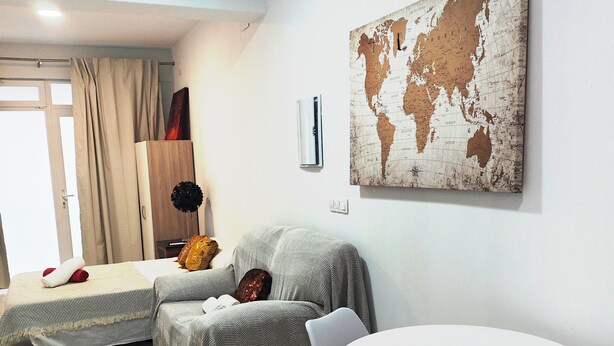 A living room with a sofa, a table, a globe artwork, and a window with curtains. - Studio MARQ CASTILLO Alicante Playa. Clean and complete. Well communicated. (Alacant)