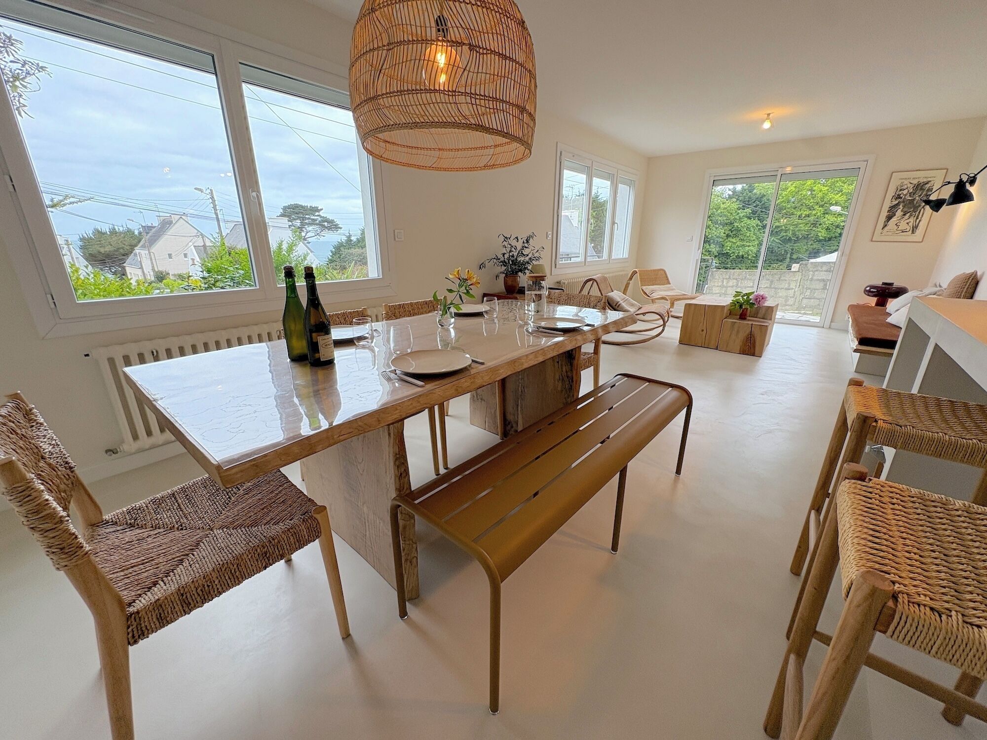Un coin repas avec une table en bois, des chaises en osier et un luminaire suspendu.