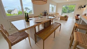 Ein Essbereich mit Holztisch, Korbstühlen und einer Hängelampe.