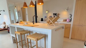 Eine moderne Küche mit Kochinsel, Barhocker, Pendelleuchten und Holzschnitzereien.