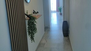 A hallway with a striped wall, a mirror, a shelf with plants, and a large vase. - La cala "Tourism & Holidays" Swimming Pool & Parking (La Cala del Moral)