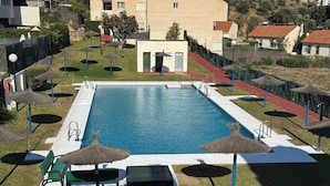 A swimming pool with a surrounding deck, lounge chairs, and umbrellas. - La cala "Tourism & Holidays" Swimming Pool & Parking (La Cala del Moral)