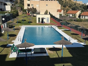 Ein Pool mit Sonnendeck, Liegestühlen und Sonnenschirmen.