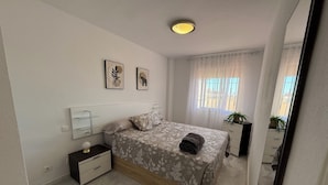 A bedroom with a bed, bedside tables, a nightstand, a mirror, and a window with curtains. - La cala "Tourism & Holidays" Swimming Pool & Parking (La Cala del Moral)