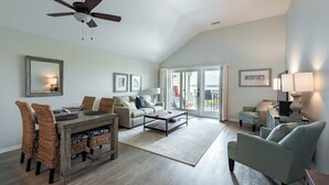 A spacious living room with a dining area, a sofa, a coffee table, and a ceiling fan.