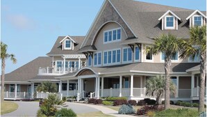 A large, multi-story house with a prominent front porch, multiple windows, and a well-maintained lawn.