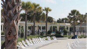 A poolside area with lounge chairs, palm trees, and a covered seating area.