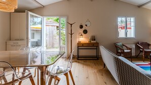 Ett rymligt rum med ett glasbord, genomskinliga stolar, en soffa, ett trägolv och ett stort fönster.
