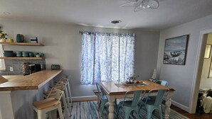 A dining area with a wooden table, chairs, and a striped rug. -  Charming 3 bed/2 bath house in Rock Hall with a 3-min walk to restaurants/town. (Rock Hall)