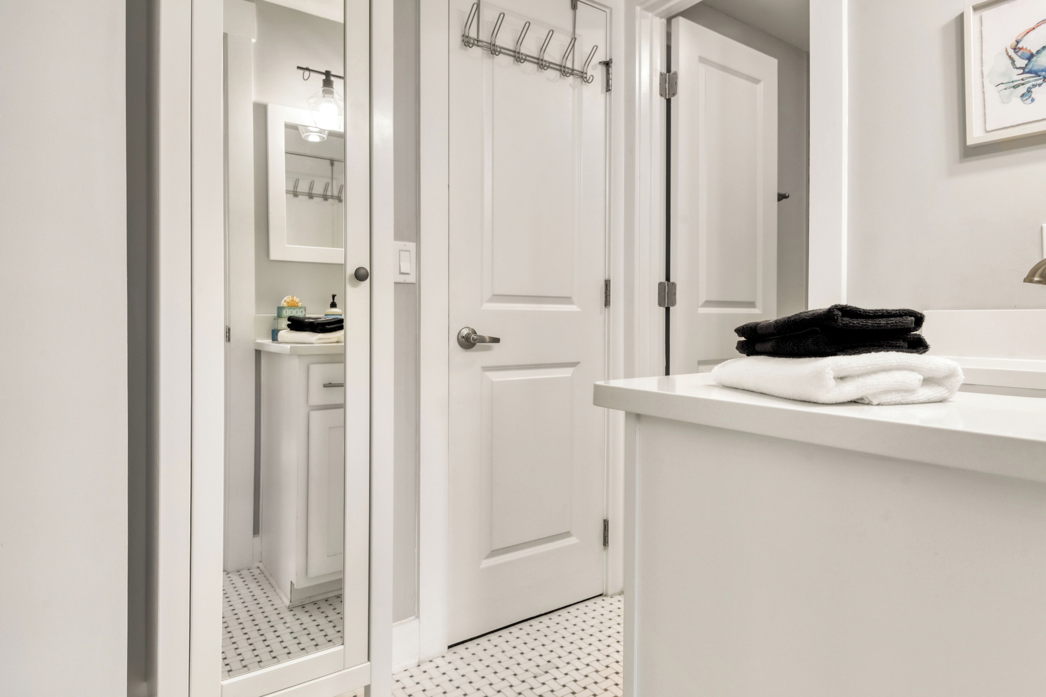 A white bathroom with a sink, mirror, and towel rack.