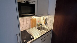 A compact kitchen with a microwave, sink, and cabinets. - Central and comfortable apartment for two or three people (Lausanne)
