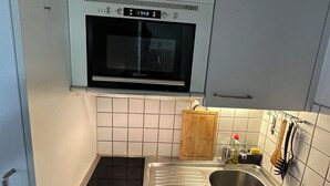 A compact kitchen with a built-in oven, a stainless steel sink, and a small countertop. - Central and comfortable apartment for two or three people (Lausanne)