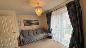 A room with a sofa, a small table, a chandelier, a painting, and a window with curtains. - Cozy Home Walk to Anfield and Liverpool Attractions (Liverpool)
