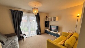 A living room with a sofa, TV, and a chandelier. - Cozy Home Walk to Anfield and Liverpool Attractions (Liverpool)