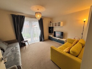 Ein Wohnzimmer mit einer Couch, einem Fernseher und einer Deckenleuchte.
