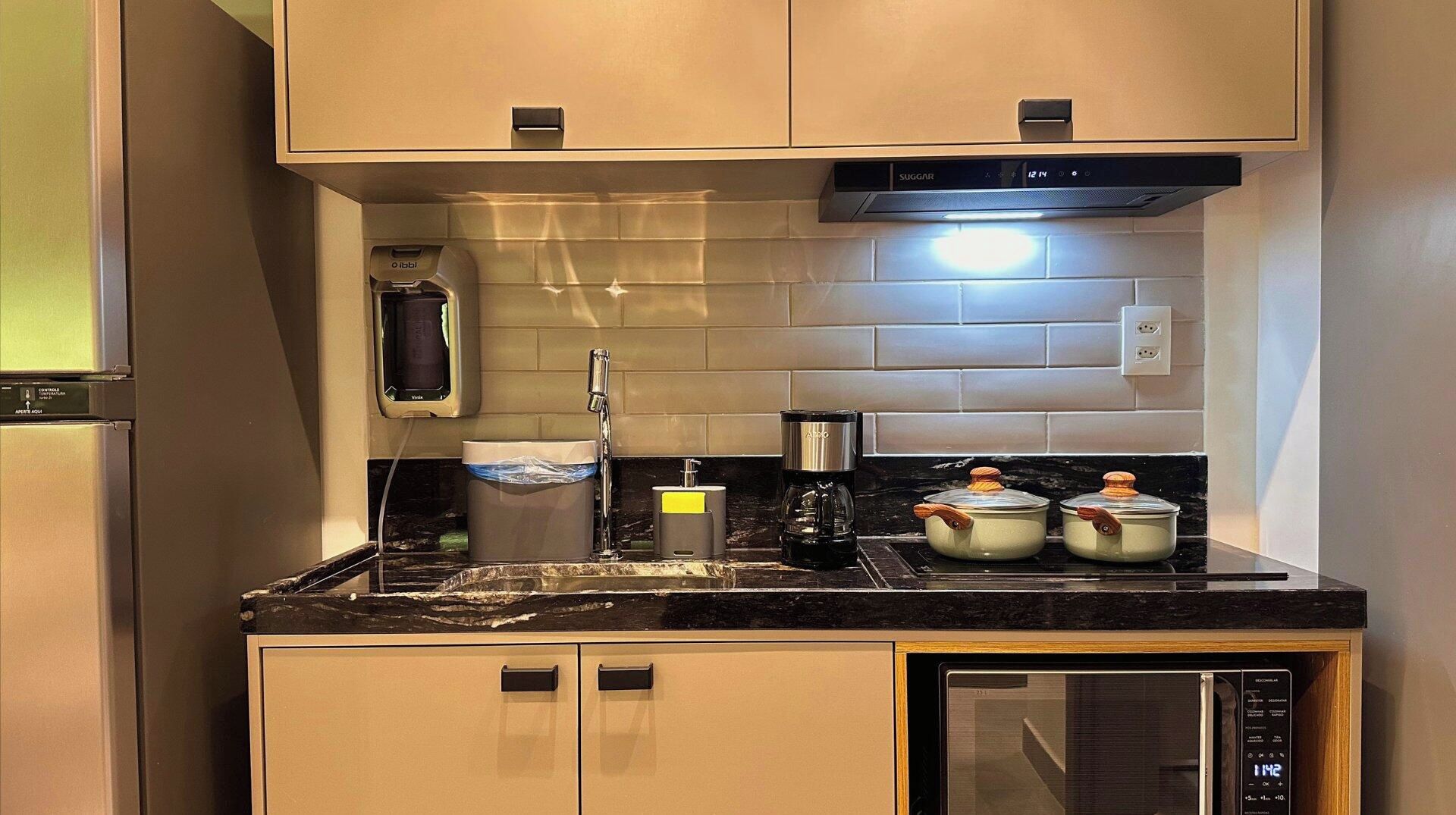 A compact kitchen with a built-in microwave, a coffee maker, and a kettle.