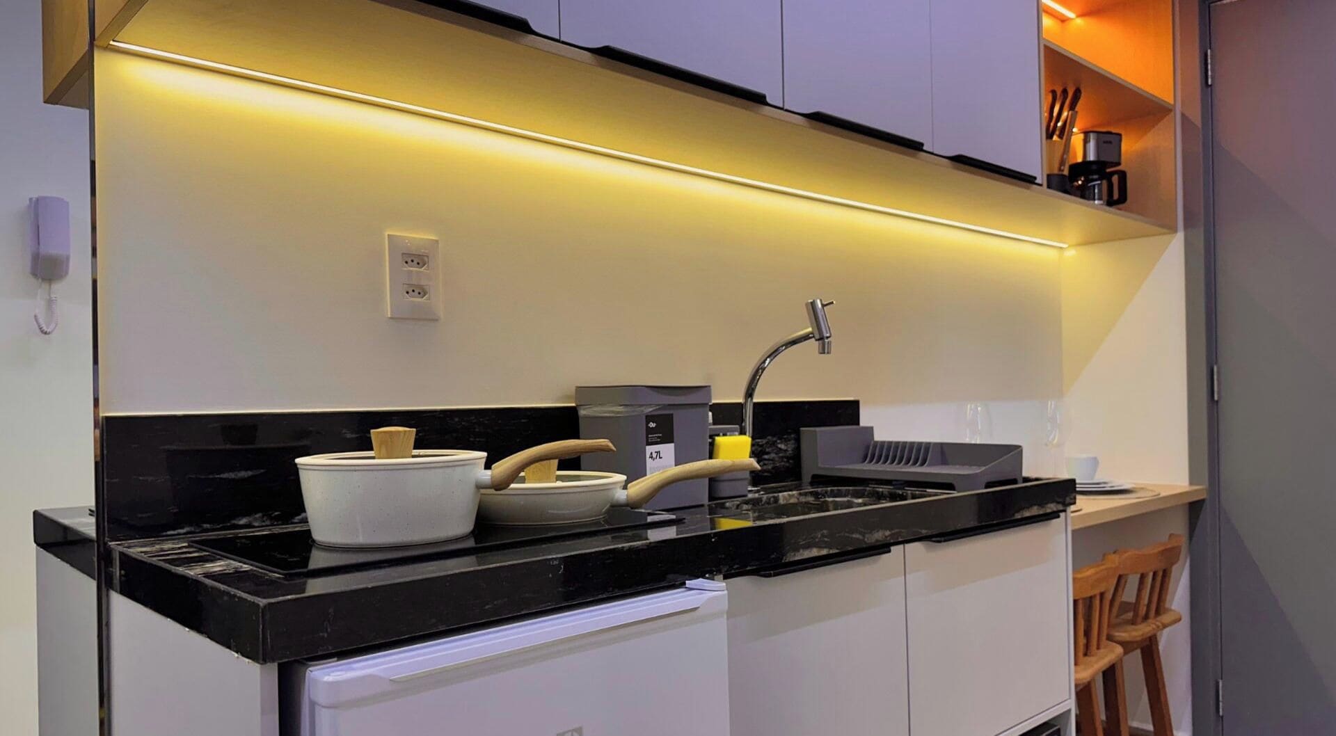 Una cucina moderna con piano di lavoro nero, pensili bianchi, forno integrato e macchina per il caffè.