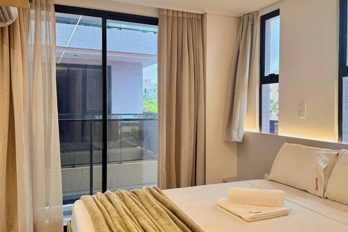 Una habitación de hotel con cama, cortinas, ventana y balcón.