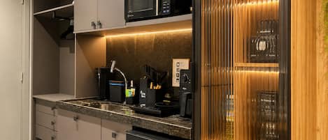 A modern kitchen with a built-in microwave, a coffee machine, and a wine cooler.