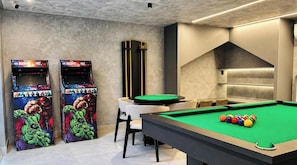 A pool table with balls, two arcade machines, a billiards table, and a seating area. - Hit Cabo Branco IV - LikeHome  (João Pessoa)