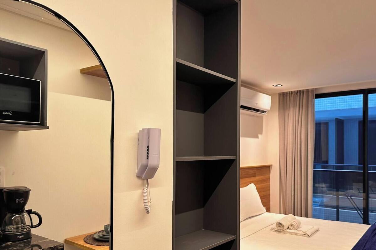 Habitación de hotel con televisión, teléfono, cafetera y cama con vista a la ciudad.