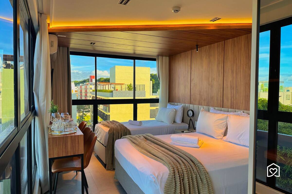 Una habitación de hotel moderna con una cama grande, un escritorio con silla y vistas a la ciudad.