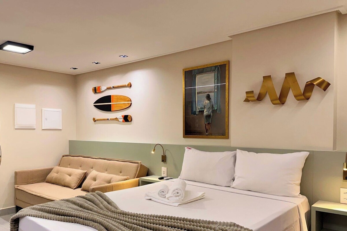 Habitación de hotel con cama, sofá, espejo, un cuadro y una pared decorada.